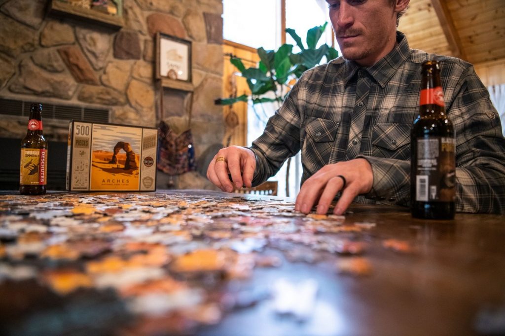 man in blue KÜHL flannel doing a puzzle