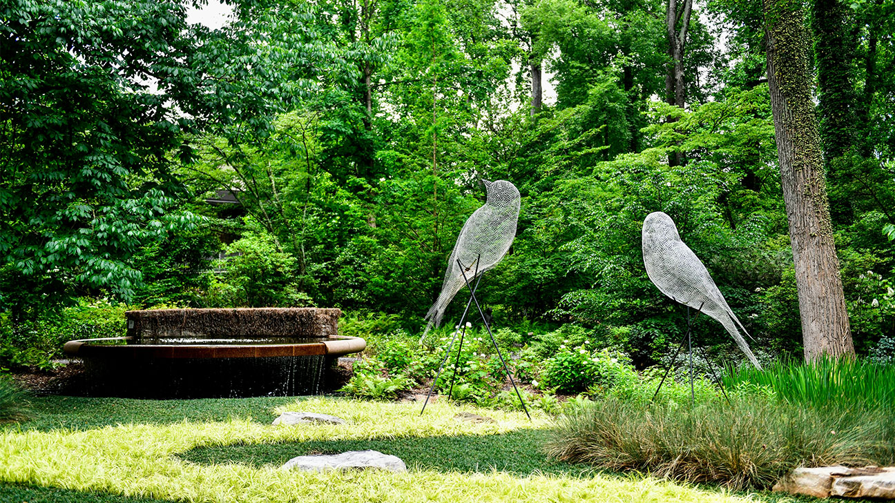The image shows the iconic "Luminous Wire Birds" sculpture installation by French artist Cédric Le Borgne